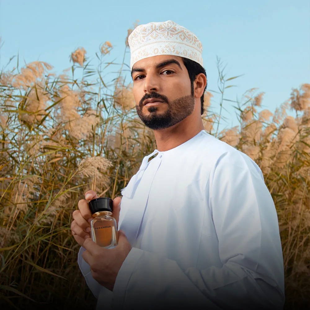 A man holding a bottle of Wanderlust in tall grass